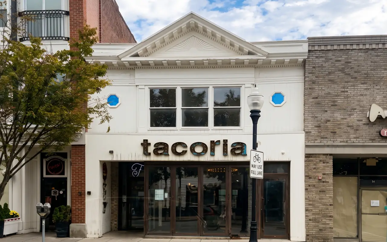 The white two-story building at 52 South Street, seen from the sidewalk. The apartment is the second floor, behind the three tall front windows.